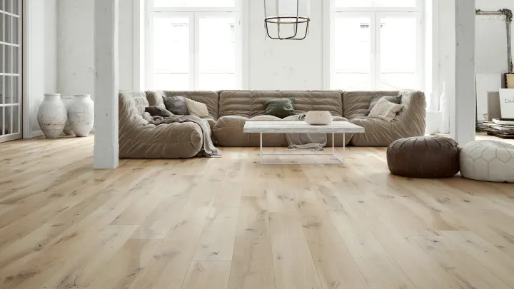 Loftový obývací pokoj s béžovou sedačkou a bělenou dubovou podlahou Barlinek Dub Ivory Grande