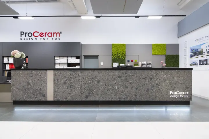 Recepční pult s obkladem v tmavém kamenném designu a podsvíceným logem v showroomu