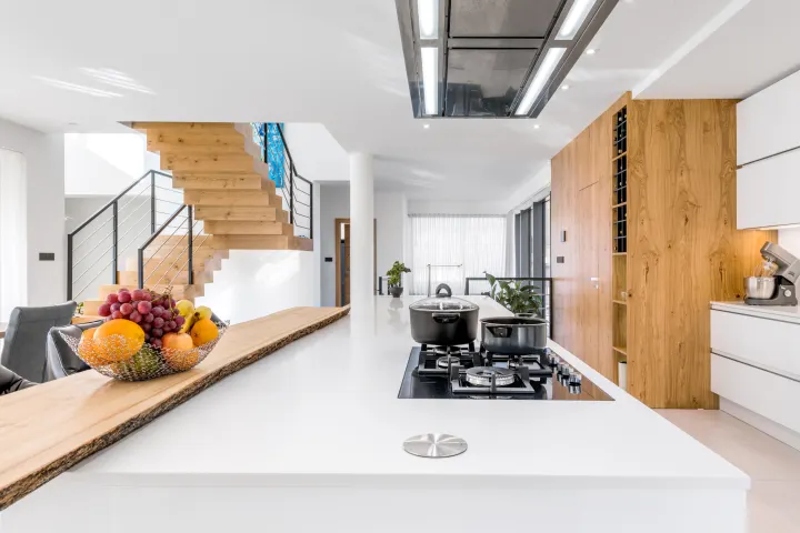 Prodloužený bílý ostrůvek s plynovou varnou deskou a dřevěnou deskou baru